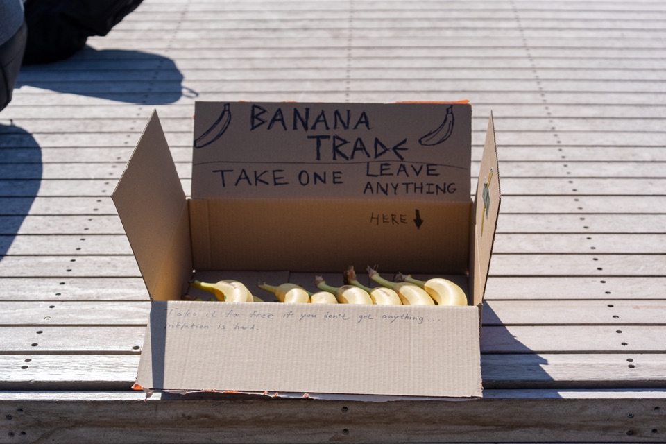 A box of bananas with handwritten TAKE ONE / LEAVE ANYTHING instructions