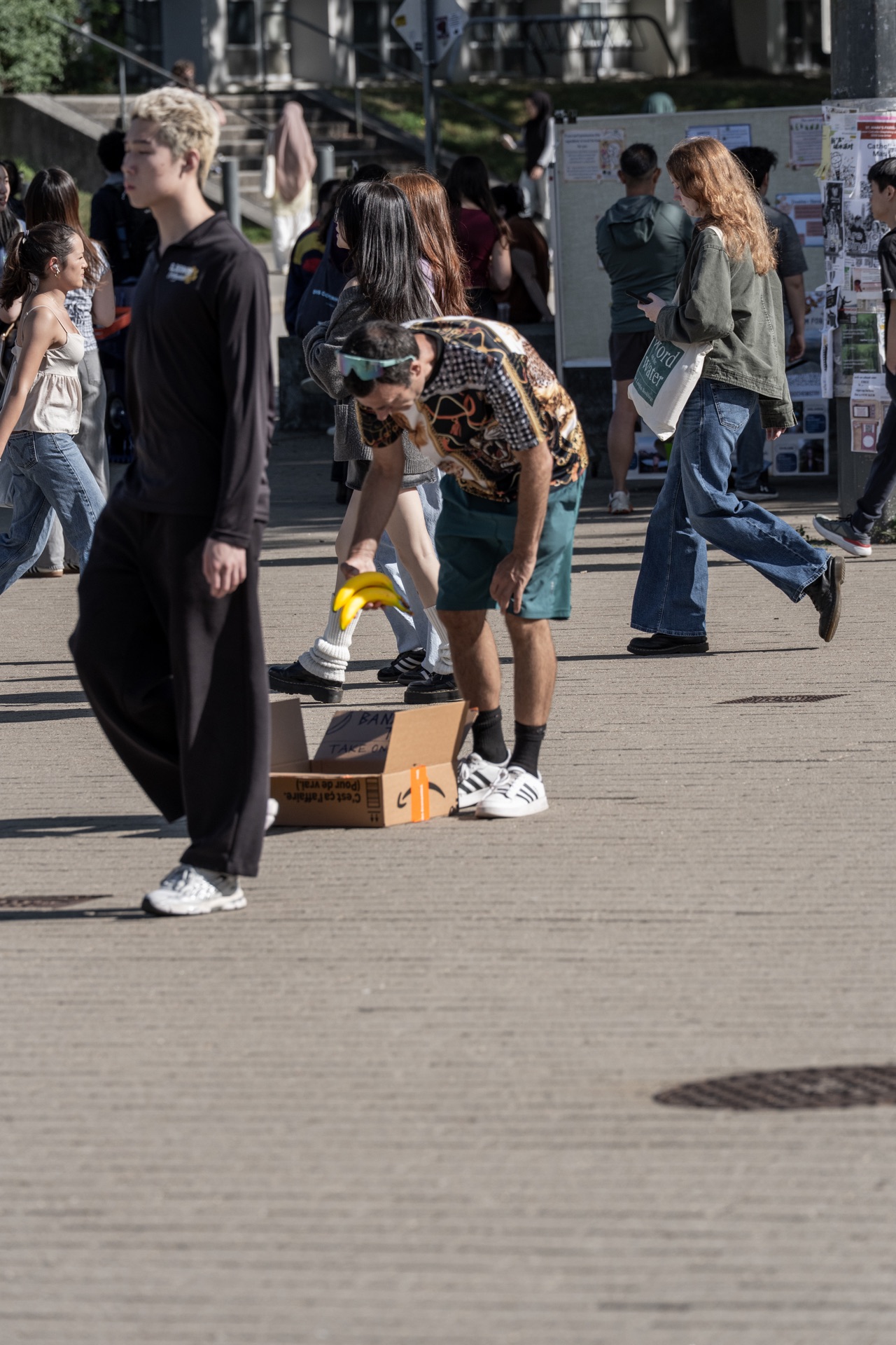 A participant bends down and picks up bananas from the box