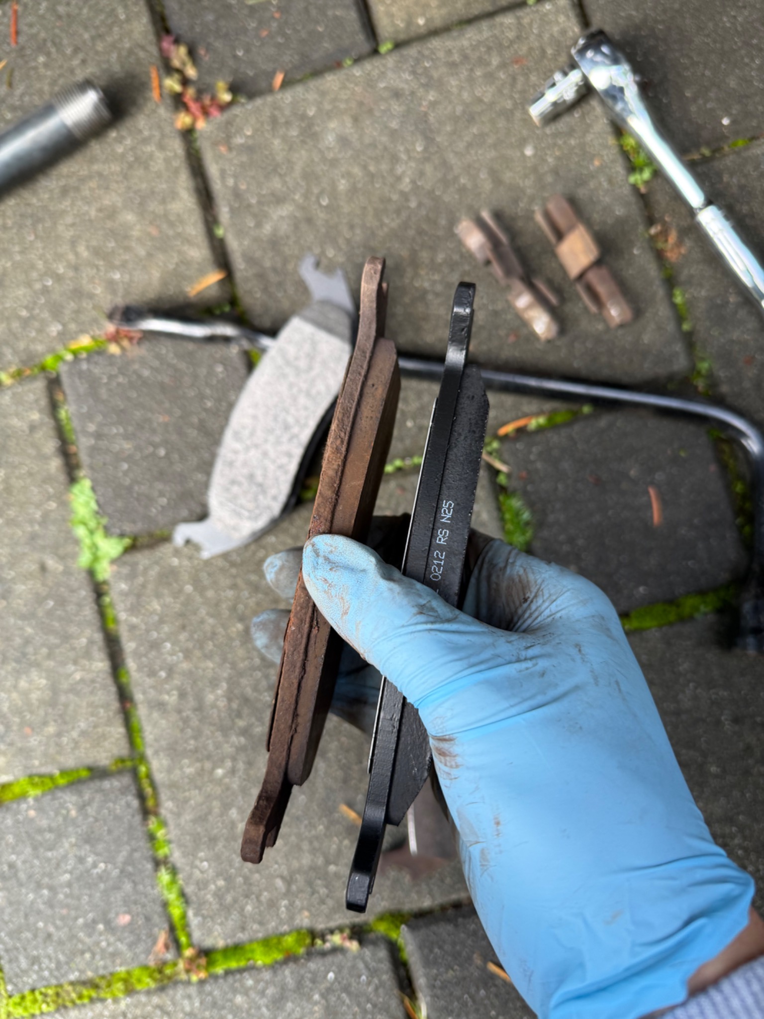 Old and new brake pads held side by side during a Ram 1500 brake service